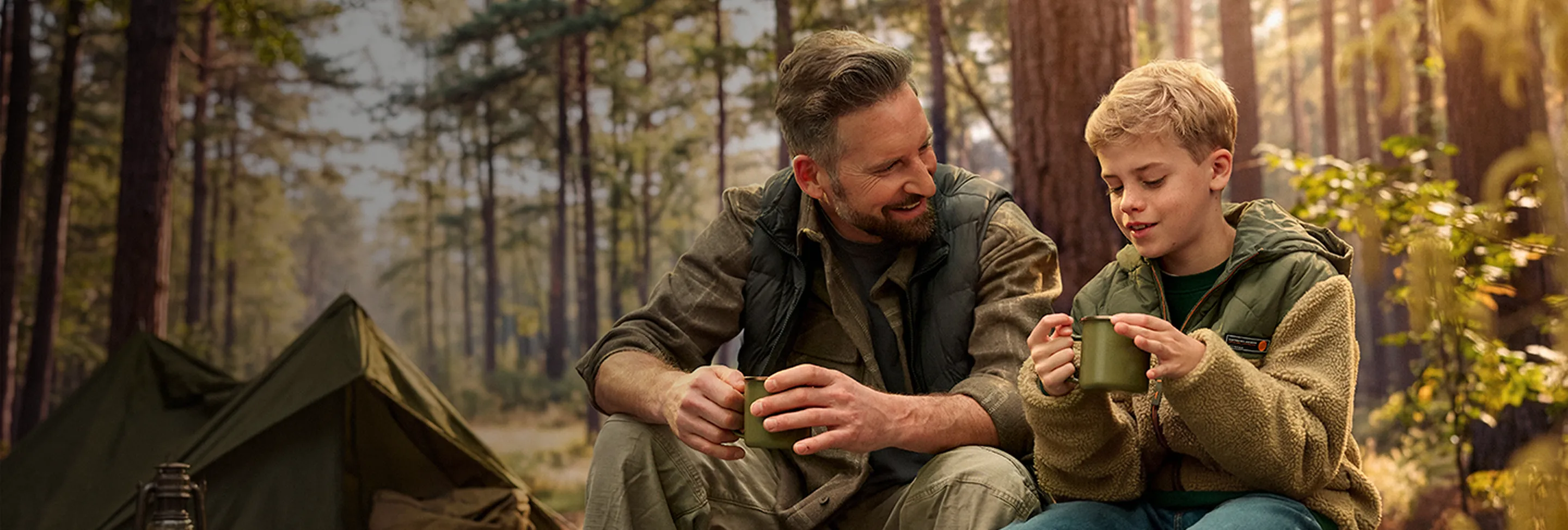 Mann und Junge sitzen vor einem Zelt im Wald